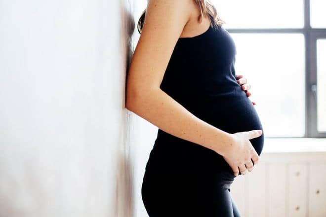 Pregnant woman standing with hand on belly
