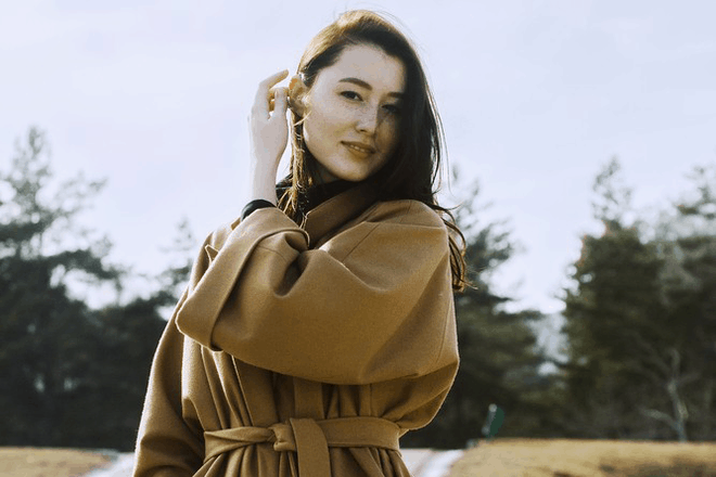 Woman in tan coat outdoors, editorial portrait